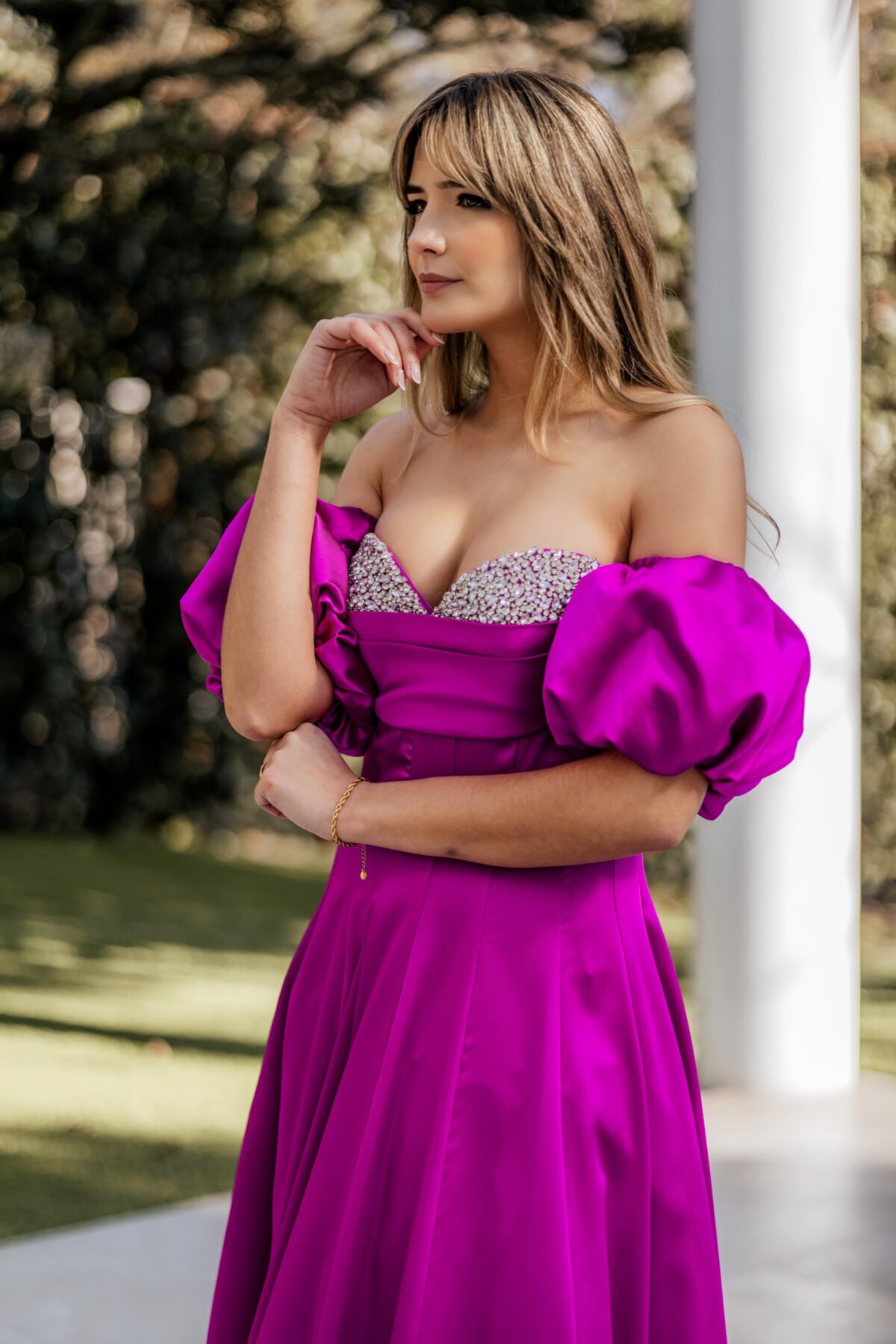 Detalhe do decote estruturado com aplicação brilhante no vestido de festa fúcsia.